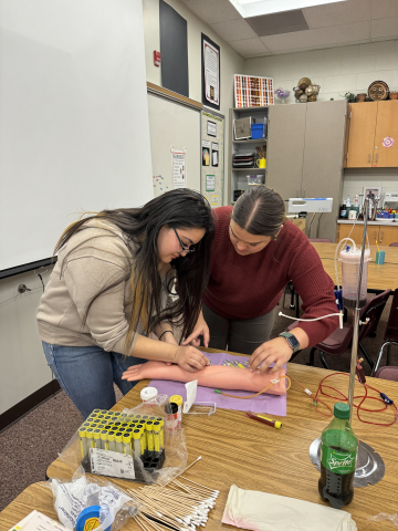 Edna practicing Phlebotomy with help from MTech 