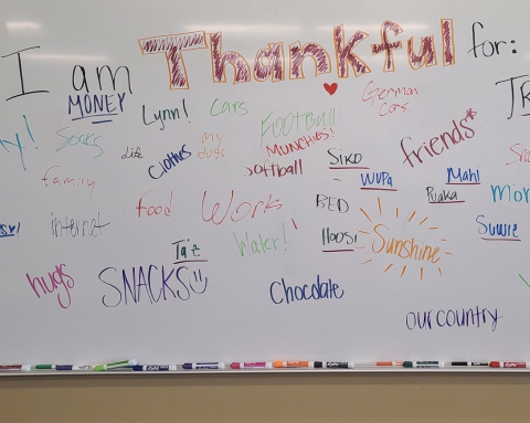 Students write what they are thankful for on the whiteboard 