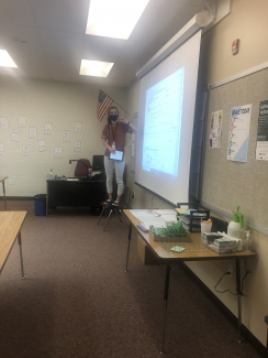 Teacher standing on chair to reach projected material